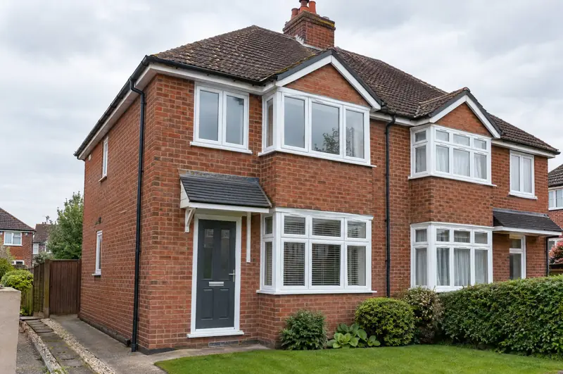 White uPVC casement windows on a 1930s red-brick semi-detached house