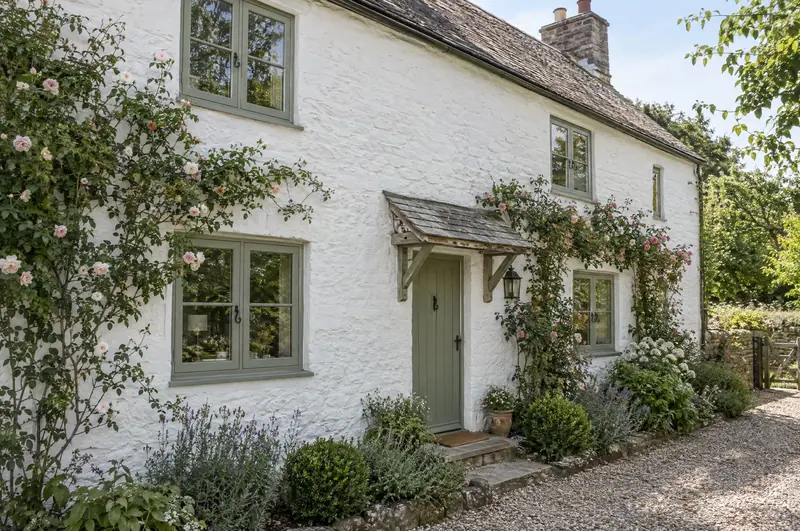 Sage green flush casement windows on a whitewashed English cottage
