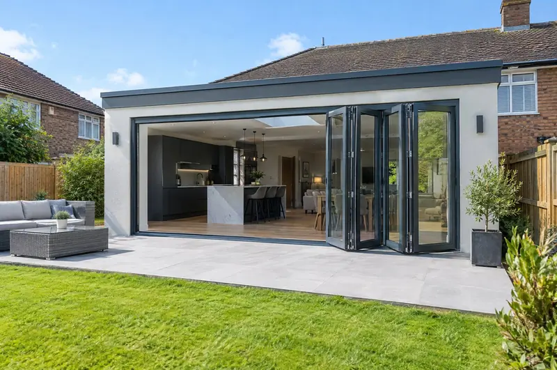Anthracite aluminium bifold doors partly folded on a single-storey rear extension