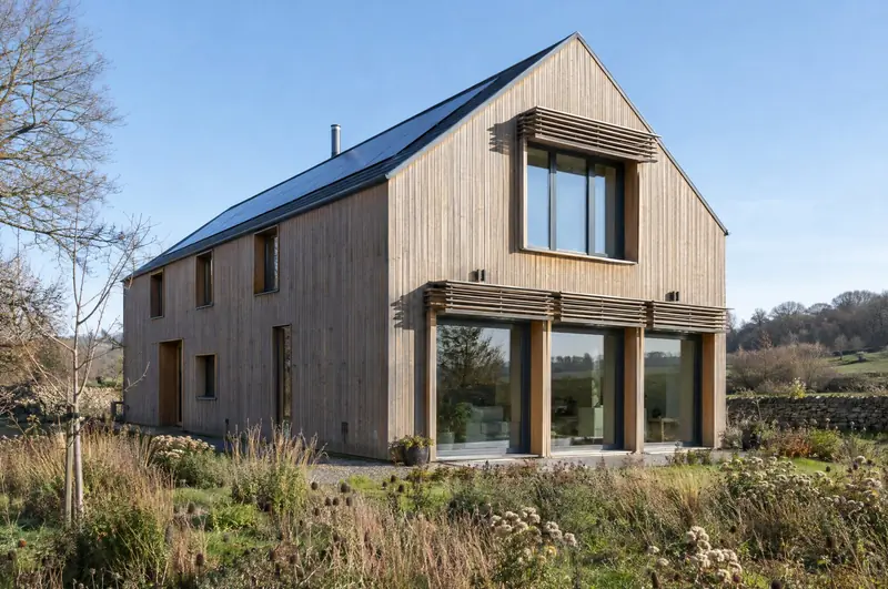 Timber-clad low-energy house with deep-set windows and external shading